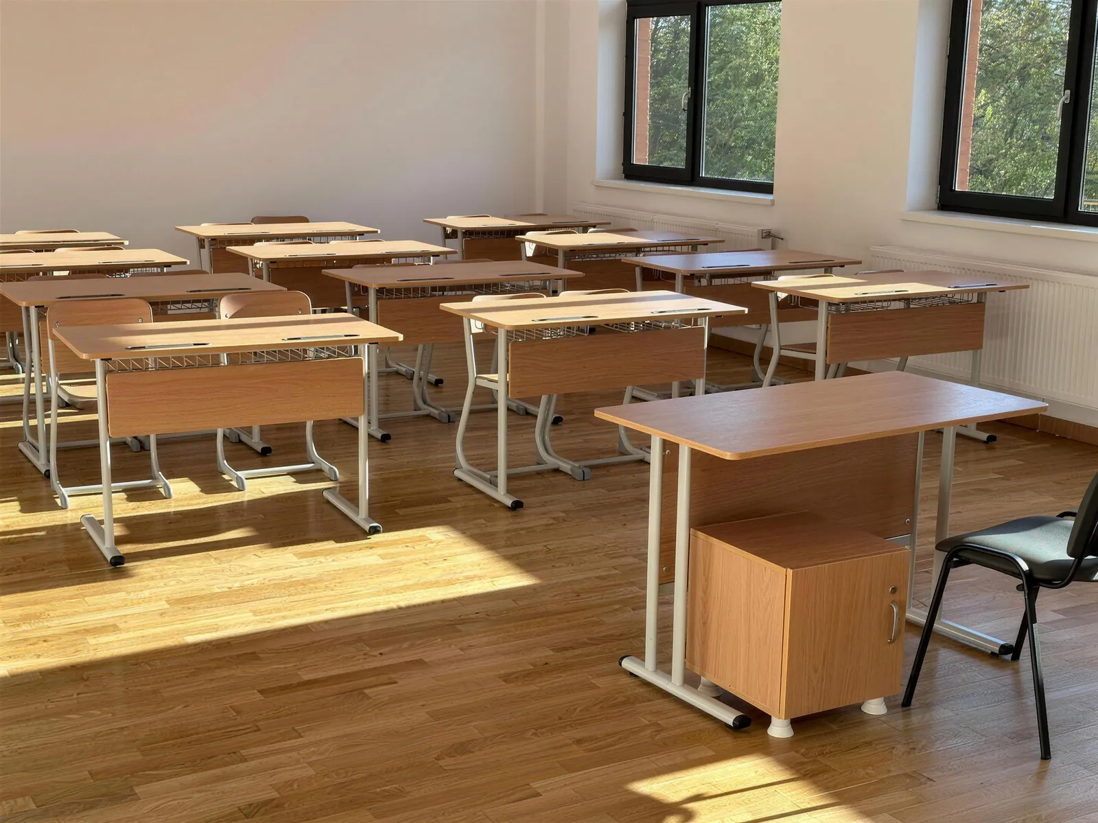 Salle de cours avec tables d'élèves en bois et bureau de l'enseignant avec caisson