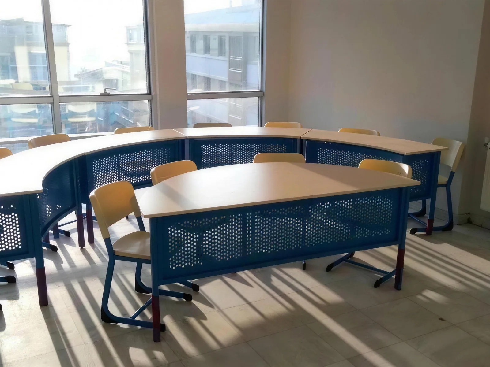 Tables à panneaux en métal perforé disposées en U et chaises en bois